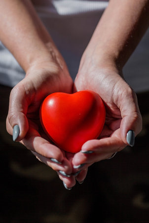 Women's hands hold a red heart. World Health Day, Love and Family Insurance. World Heart and Health...