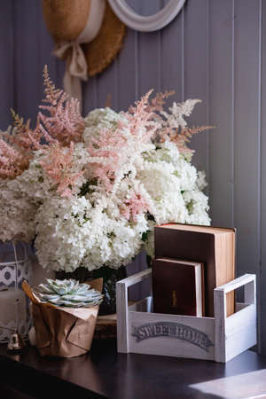 Details of a still life in the home interior of the living room. Books, a vase with hydrangea and astilba flowers, succulent. Read and relax. Cozy home concept.の写真素材