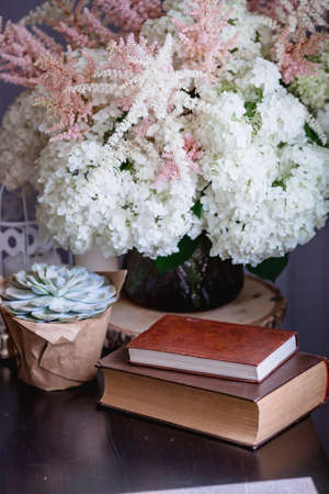 Details of a still life in the home interior of the living room. Books, a vase with hydrangea and astilba flowers, succulent. Read and relax. Cozy home concept.の写真素材