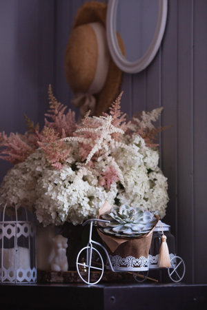 A succulent on a decorative bicycle and a bouquet of white hydrangeas and astilba. Interior in Provence style. A concept for a flower shop or home comfort and decor in the house.の写真素材