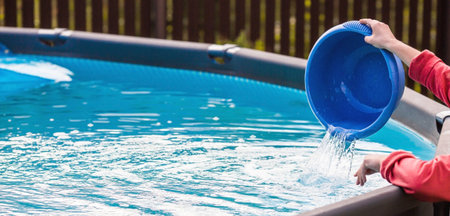 Cleaning a swimming pool with a metal frame with a net from leaves and dirt. Pool cleaner during...