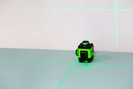 Construction and finishing works indoors. Laser construction level with green beams on the wall. Apartment renovation and construction work.の写真素材