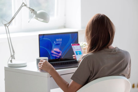 A young, happy, beautiful freelance business woman sitting in a home office with a laptop and a...