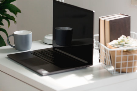 Freelance. The office is in bright colors. A white table with a laptop, books, a mug, a flower and a...