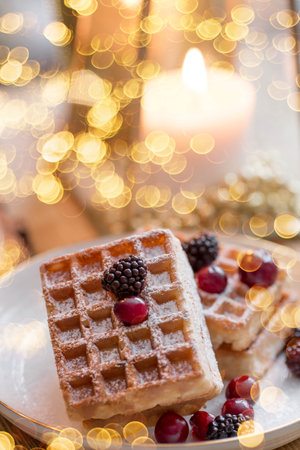 Lifestyle.A cup of tea, waffles, a Christmas tree and candles on a wooden table on a beautiful bokeh background during the Christmas holidays. still life. The concept of home warmの写真素材