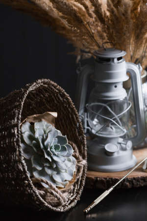 Candles, succulent, basket and a beautiful bouquet of dried pampas grass flowers in a glass vase on a dark table. An element for decoration and interior decoration.の写真素材