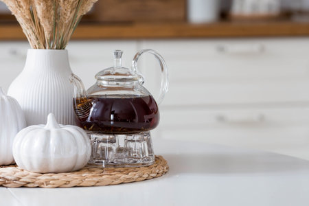 still life. Pampas dried grass in a vase, white ceramic pumpkins and a teapot on a white table in the interior of a Scandinavian-style home kitchen. Cozy, stylish autumn concept.の写真素材