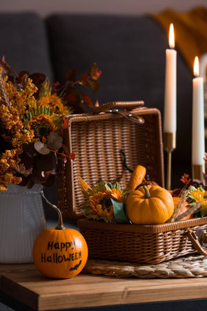 A wicker basket with pumpkins, Jack's Pumpkin and candles in the interior of the living room on a wooden table. The concept of home comfort. Autumn decor for Halloween.の写真素材
