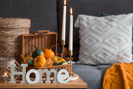 Cozy autumn concept. Home warmth in cold weather. still life. Pumpkins, wicker basket, candles and flowers on the coffee table in the home interior of the living room.の写真素材