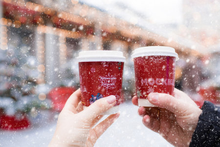A New Year's cup with hot coffee in the hands of a married couple. The inscription on the cups: "Moscow and a Journey to Christmas." New Year's mood.の写真素材