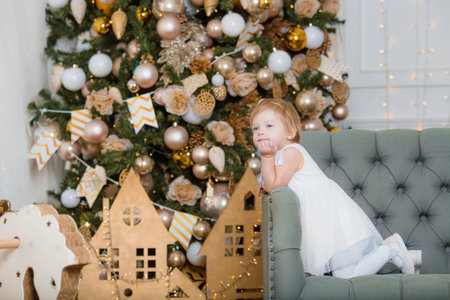 Merry christmas and happy new year! Portrait of a beautiful little one-year-old girl on the sofa in...