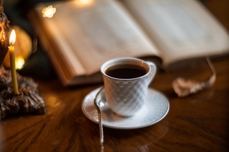 Autumn still life with beautiful bokeh. A cup of coffee and a book on a wooden table through wet glass.の写真素材