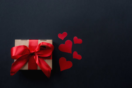 Gift box and red hearts on a black background. Layout for creating a card for Valentine's Day.の写真素材