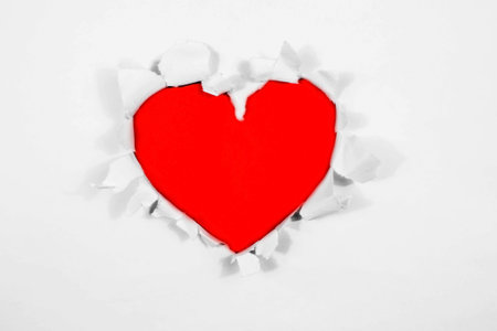 Red hearts, an envelope, and a white sheet of paper for text on a blue background with copy space....