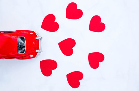 Red retro toy car and red hearts on white background. February 14 postcard, Valentine's Day.