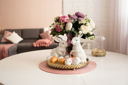 Scandinavian style of interior.Golden easter eggs, unicorn eggs and white rabbits on a white wooden kitchen table. minimal concept. Card with copy space for text.の写真素材
