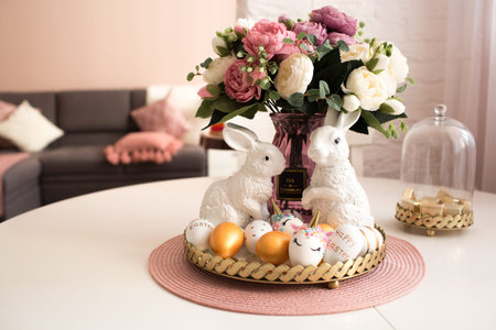 Scandinavian style of interior.Golden easter eggs, unicorn eggs and white rabbits on a white wooden...