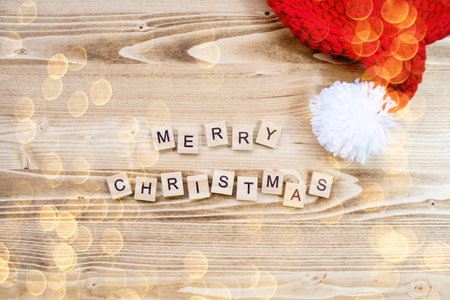 Banner. The inscription of wooden letters merry Christmas, Santa Claus hat on a wooden background. The concept of celebrating the winter New Year holidays 2022.の写真素材
