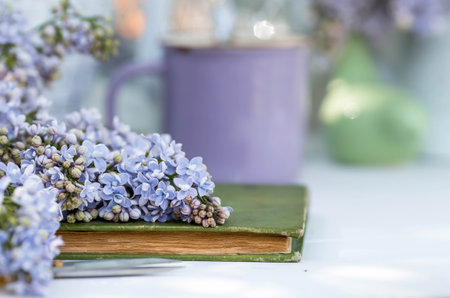 The postcard is beautiful. A fancy purple coffee mug, an old book and a bouquet of purple lilac. beautiful still life. springtime. The concept of "Good morning".の写真素材