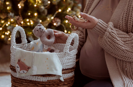 A young pregnant woman holding her tummy against the background of a Christmas tree. close-up. A...