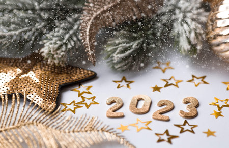 Happy New Year and Merry Christmas. Golden numbers 2023, snow, fir branches, Christmas tree toys and...
