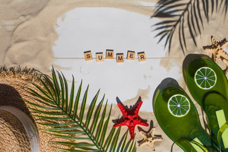 The concept of a holiday at the sea. Seashells, stars, a straw hat, bikinis, sunglasses, lime flip-flops and maracas on the sand. Background for summer holidays with space for text. top view.の写真素材