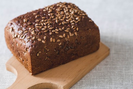 Fresh delicious whole grain rye bread with seeds close-up. Freshly baked bread on a wooden board. The context of a bakery with delicious bread. confectionery products.の写真素材