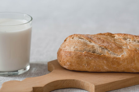 Fresh delicious bread close-up. Freshly baked sourdough bread with a golden crust on a wooden board. The context of a bakery with delicious bread. confectionery products.の写真素材