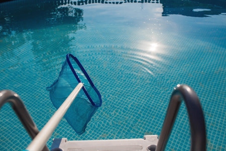 Abstract blur and defocused background. Cleaning of a swimming pool with a metal frame with a mesh from dirt. Pool cleaner during operation. Solar banner.The concept of summer holidays.の写真素材