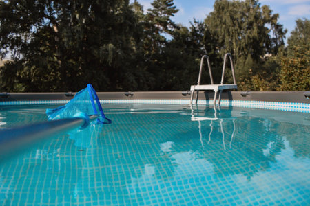 Cleaning a swimming pool with a metal frame with a net from leaves and dirt. Pool cleaner during...