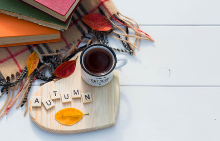 Coffee mug and wooden letters on a wooden stand in the shape of a heart on a white table. The concept of the fall season. A Cup of tea with autumn leaves. fall time. copyspace.の写真素材