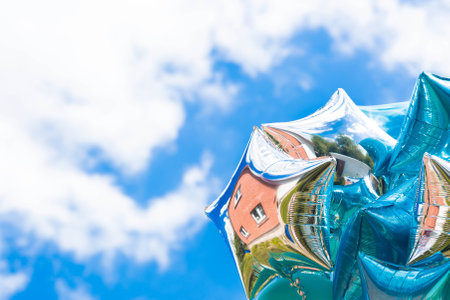 Beautiful silver and blue balloons in the form of stars in the open air on a blue sky background. The concept of freedom and celebration.の写真素材