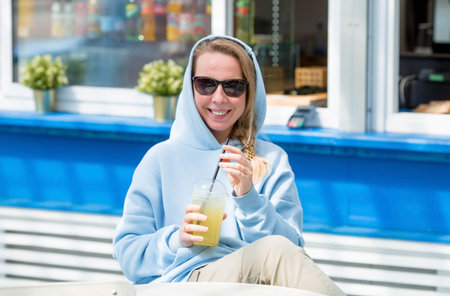 A beautiful young woman smiles while sitting in a cafe. In the hands of lemonade. The concept of...