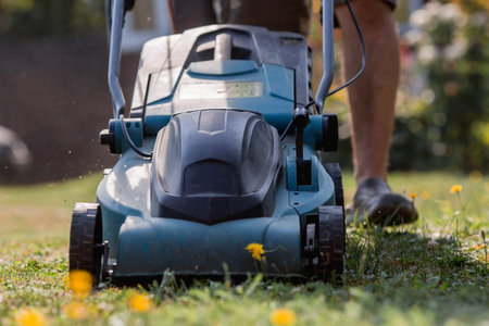 Banner. A human lawn mower cuts the grass in the backyard. Agricultural machinery for the care of...