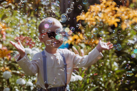 Cute happy boy playing with soap bubbles on a sunny summer day. A child in the fresh air, in nature. The concept of a happy childhood and a holiday.の写真素材