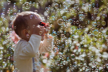 Cute happy boy playing with soap bubbles on a sunny summer day. A child in the fresh air, in nature. The concept of a happy childhood and a holiday.の写真素材