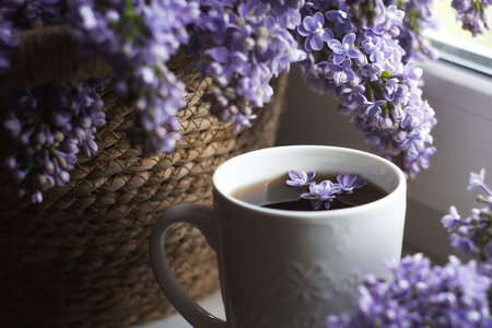 Cup of coffee and a lilac flower. Spring coffee concept for background or copy space for text.