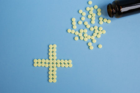 Tablets are yellow, round, medicines laid out in the form of a cross or X on a blue background. Conceptual for pharmaceutical production.の写真素材