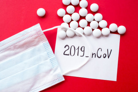 Surgical mask protective mask with text coronavirus and pills. Chinese coronavirus outbreak. red background.の写真素材