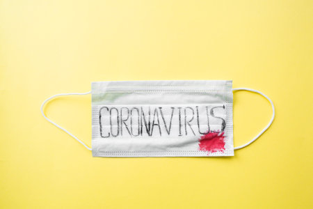 Surgical mask protective mask with text coronavirus, blood. Chinese coronavirus outbreak. yellow background. Novel coronavirus - 2019-nov, WUHAN virus concept.の写真素材