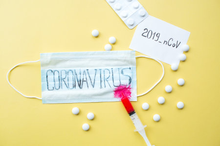 Surgical mask protective mask with text coronavirus, blood. Chinese coronavirus outbreak. yellow background. Novel coronavirus - 2019-nov, WUHAN virus concept.の写真素材