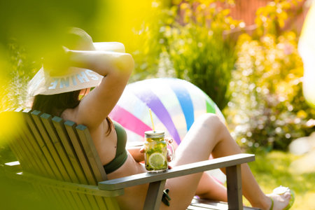 A girl in a swimsuit sitting in a deck chair with a refreshing mojito, sunbathes and enjoys the...