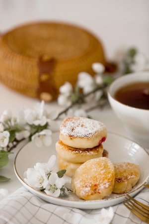 Cottage cheese pancakes with apple jam, a mug of tea and apple tree flowers. Ukrainian and Russian cuisine. Healthy morning breakfast concept.の写真素材
