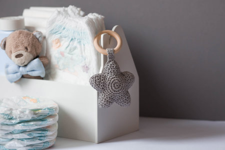 Wooden toys, a bear in a bow tie, a stack of diapers, bottles without labels and baby supplies on the changing table. Space for text.の写真素材