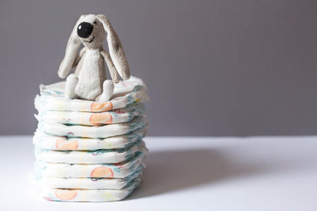 A stack of diapers and baby stuffed toys on the changing table. Space for text.の写真素材