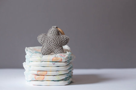 A stack of diapers and baby stuffed toys on the changing table. Space for text.