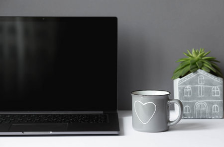 Freelance. The office is designed in light gray tones. A white table with a laptop, a flower and a...