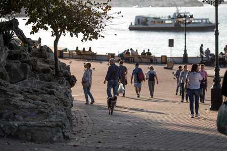 The embankment in Sevastopol in the rays of the setting sun. People are walking around the city. Russia, Republic of Crimea.のeditorial素材
