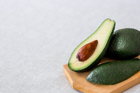Ripe delicious avocado on a cutting wooden board on a linen tablecloth. close-up. light background....