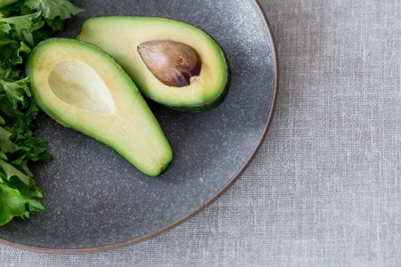 Ripe delicious avocado on a plate on a linen tablecloth. close-up. light background. Vegetarian...